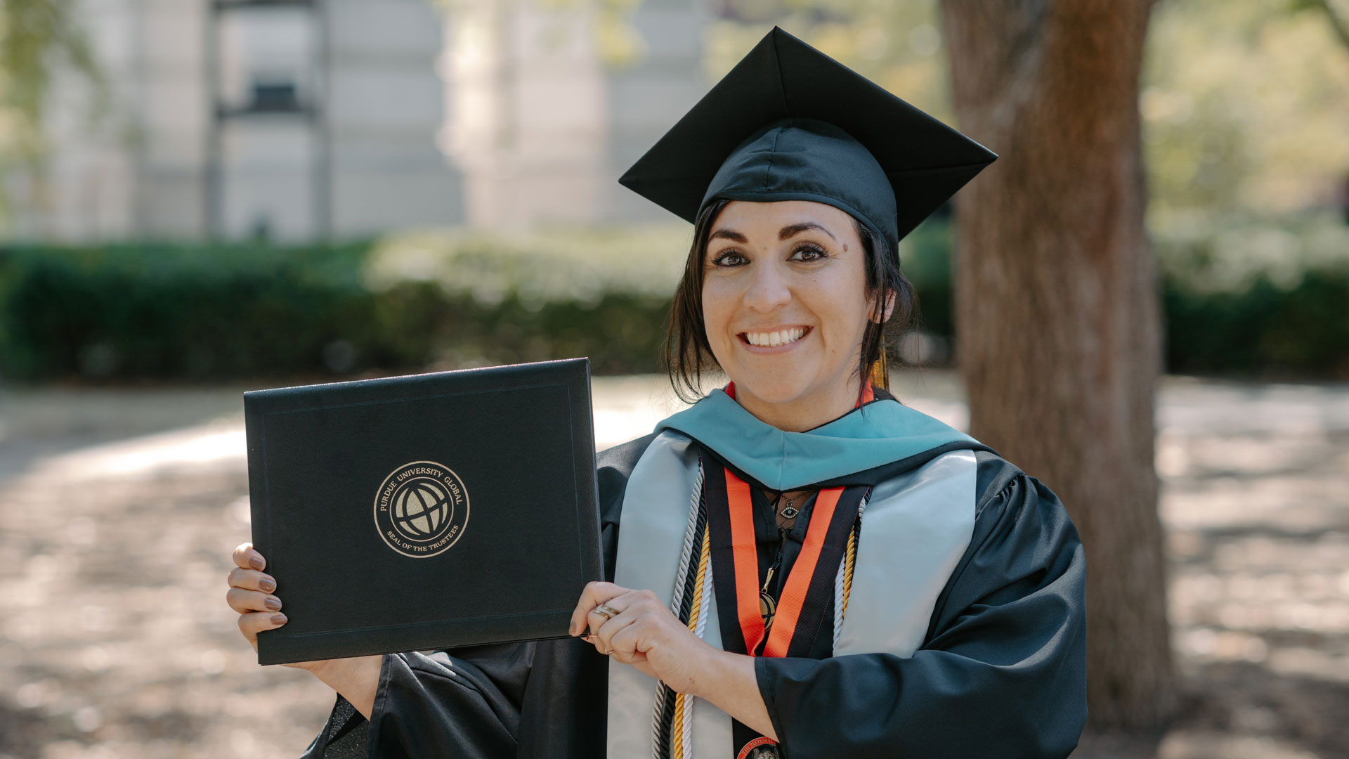 Yvette wearing a cap and gown and holding her diploma.
