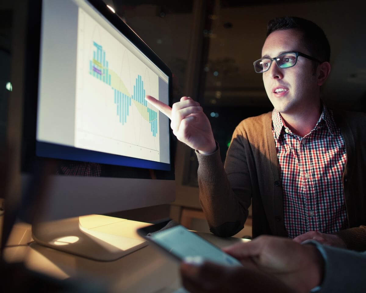 professional pointing to charts on a monitor