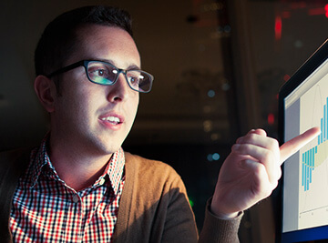 professional pointing to charts on a monitor