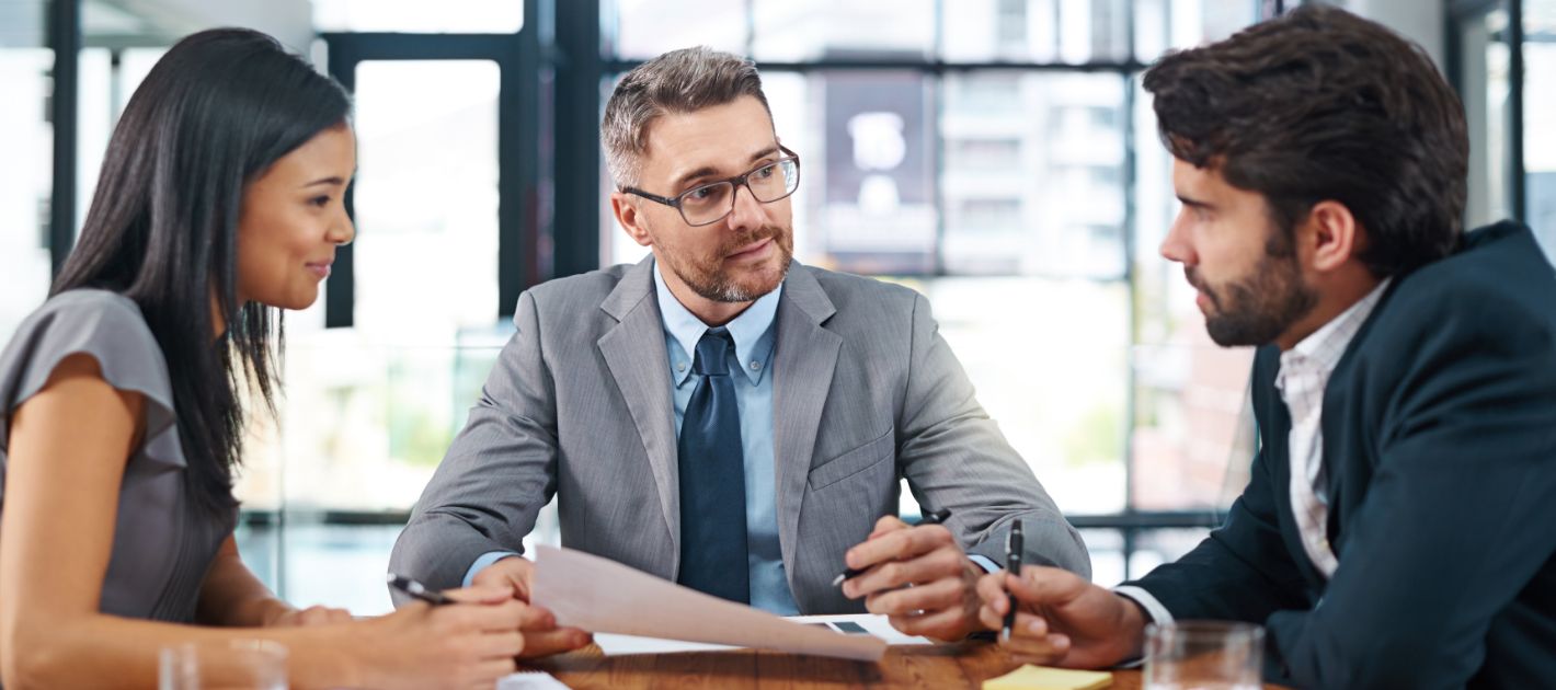 Three legal professionals reviewing documents at a modern office conference table with city view