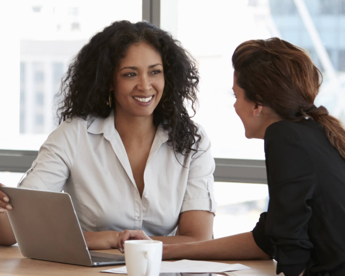 HR professionals review documents and items on a laptop in a conference room