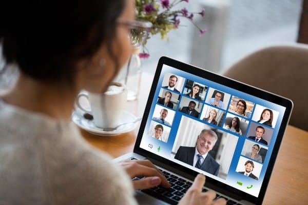 A woman looks at a laptop screen with the participants in an online dispute resolution meeting.