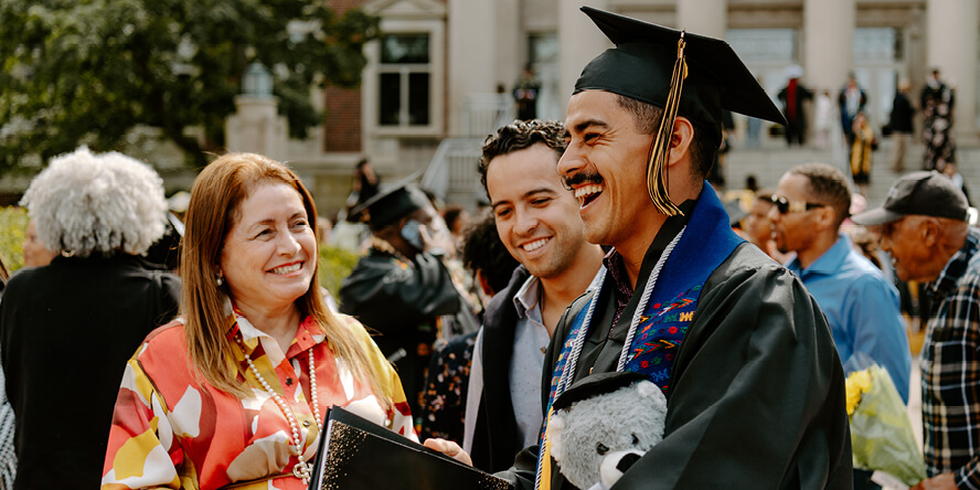 Juan, with his mom and youngest brother, laugh together outside Hovde Hall.