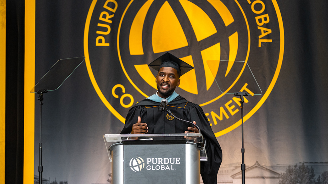 Cap: Ismail Joseph, a Purdue Global alumnus and career specialist in Purdue Global’s Center for Career Advancement, inspires graduates during October 2026 commencement ceremonies. (Purdue Global photo/Kelsey Lefever)
Alt: Purdue Global alumnus Ismail Joseph speaks at a commencement ceremony.