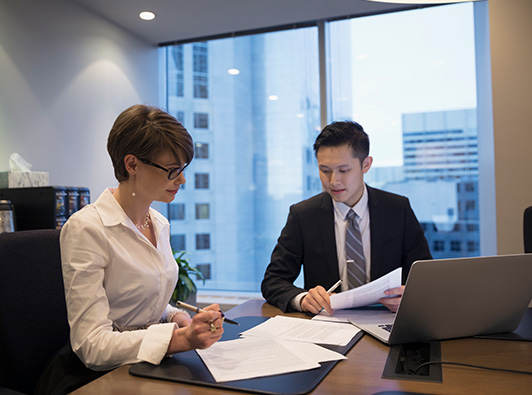 two lawyers discussing papers in a conference room