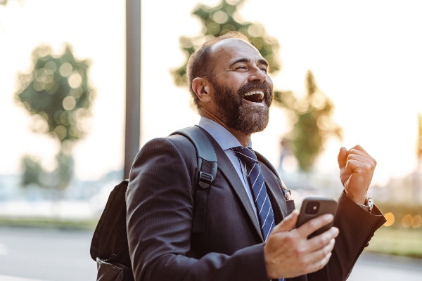 A man cheers after reading good news about a job opportunity on his smartphone.
