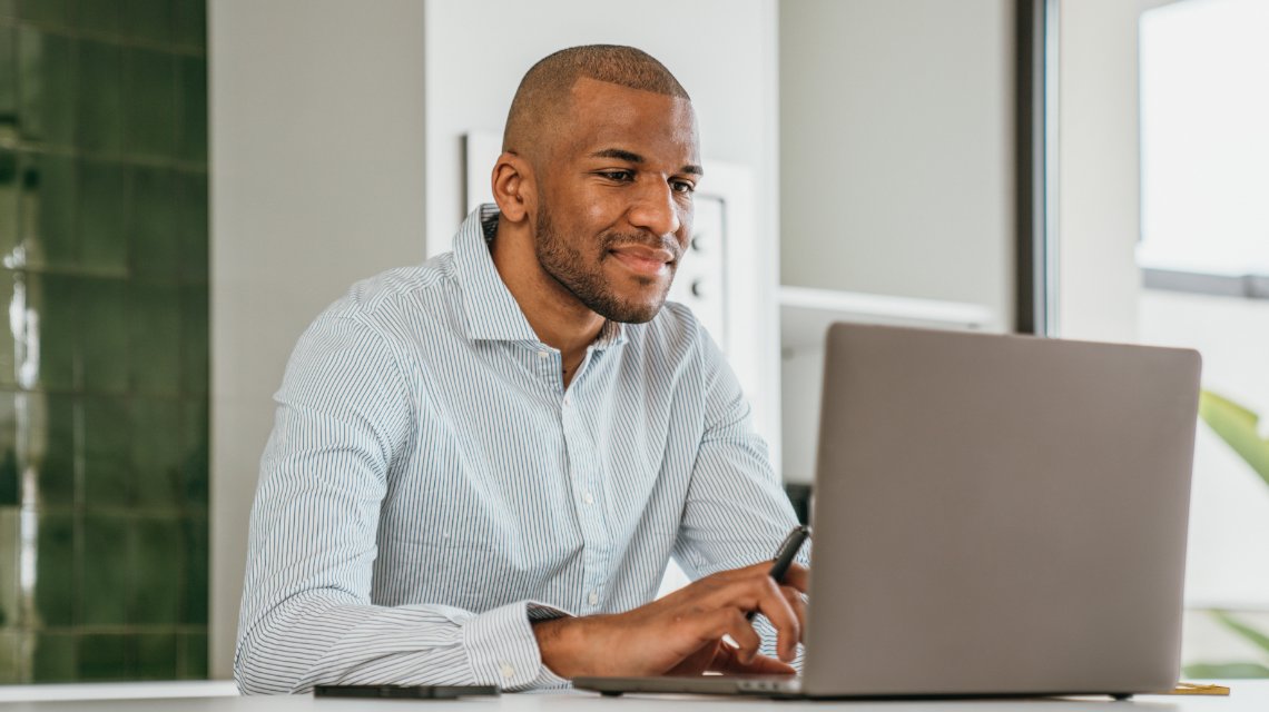 A male student reviewing his online coursework on a laptop.