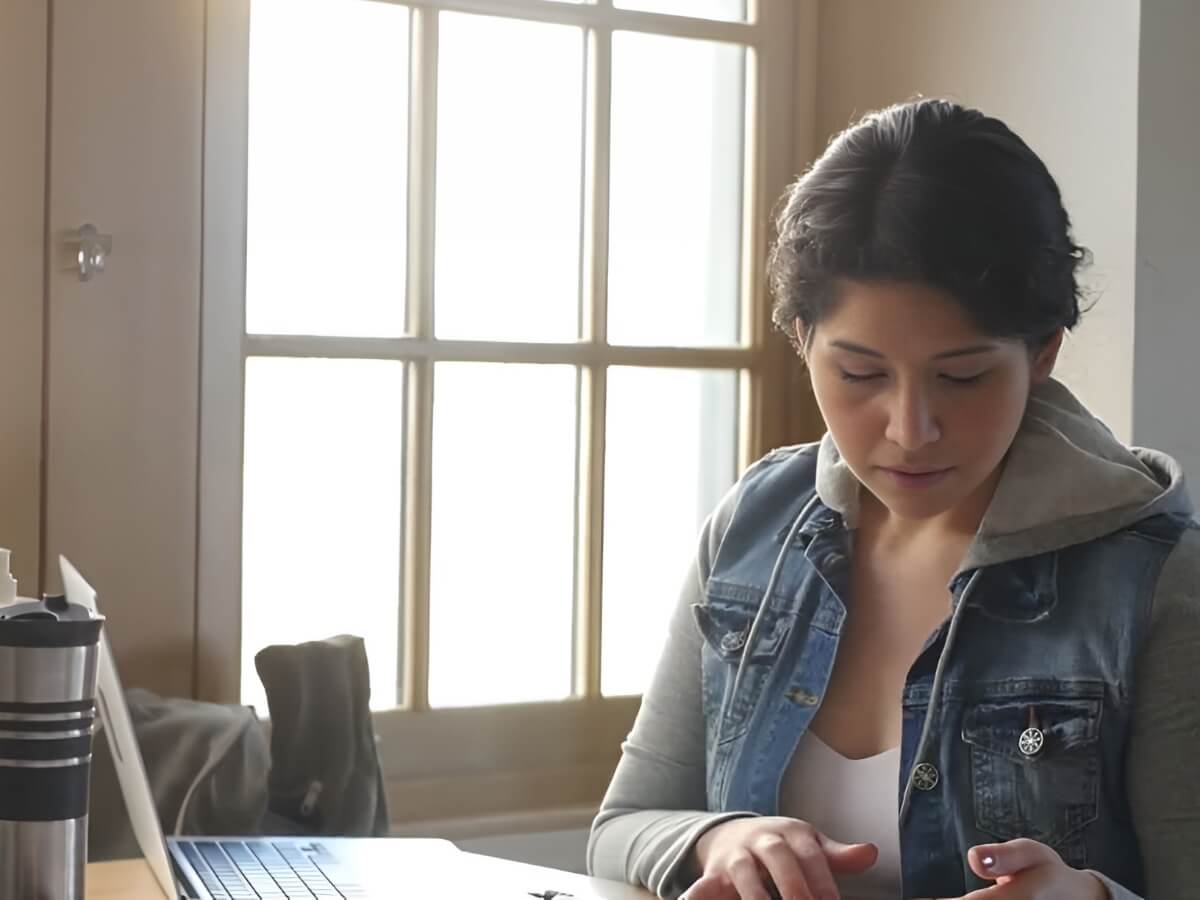 Student working on a laptop with iced coffee nearby at home