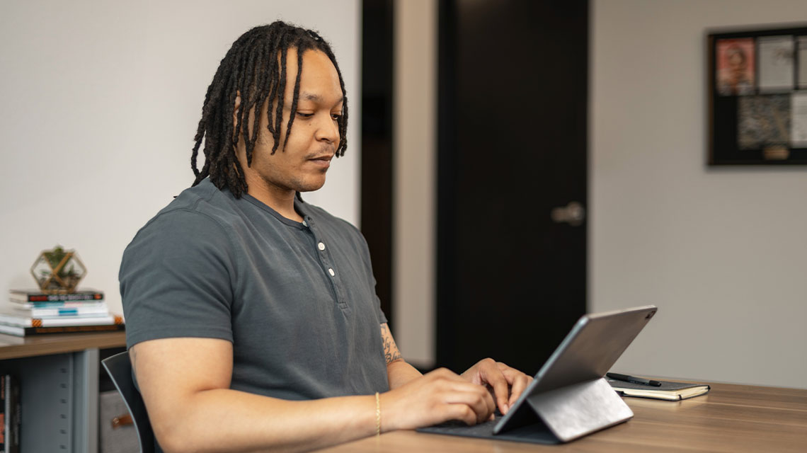 A male student researching business scholarships on his laptop.