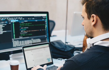 man working on laptop with additional monitors