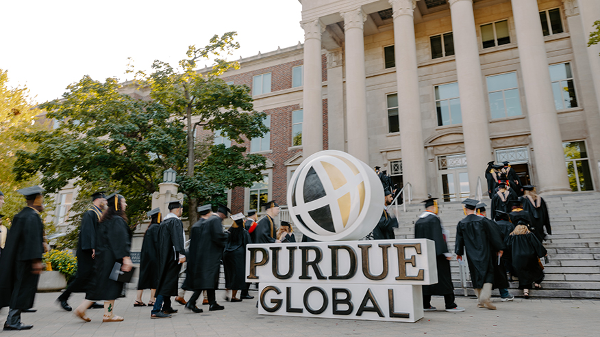 Purdue Global graduates walking up steps in front of Hovde Hall