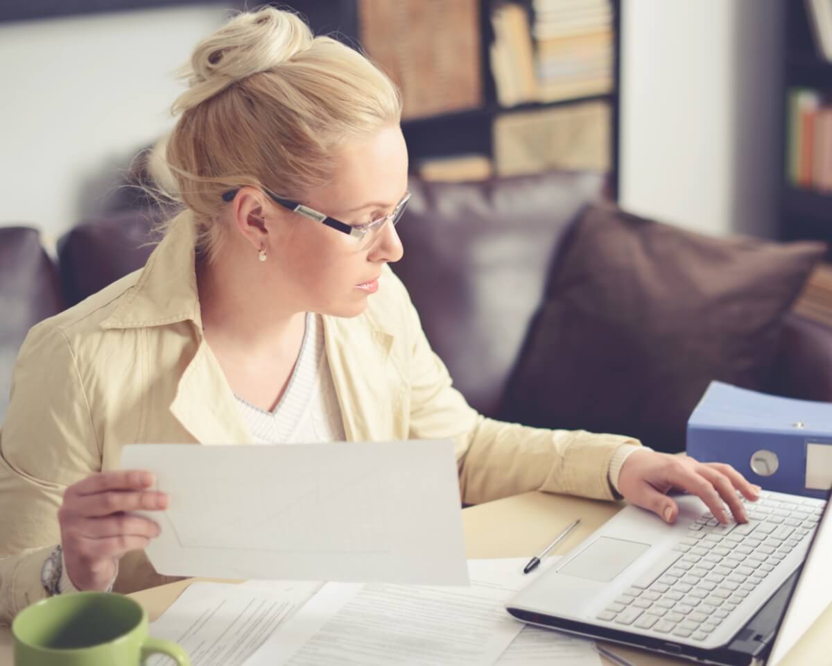 Businesswoman working on a laptop with books next to her