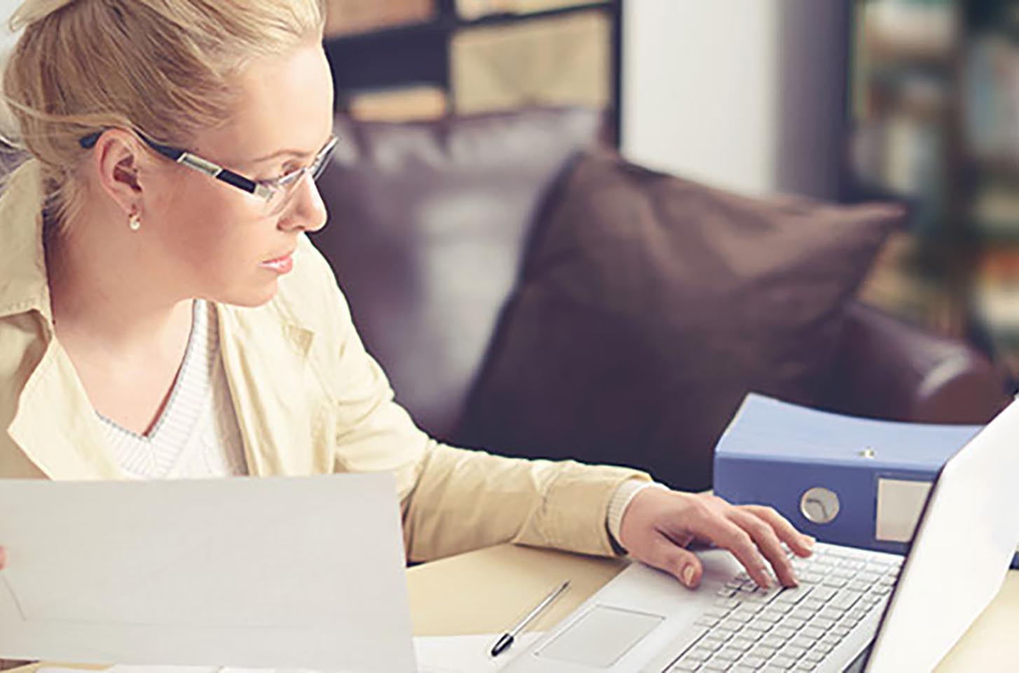 Businesswoman working on a laptop with books next to her