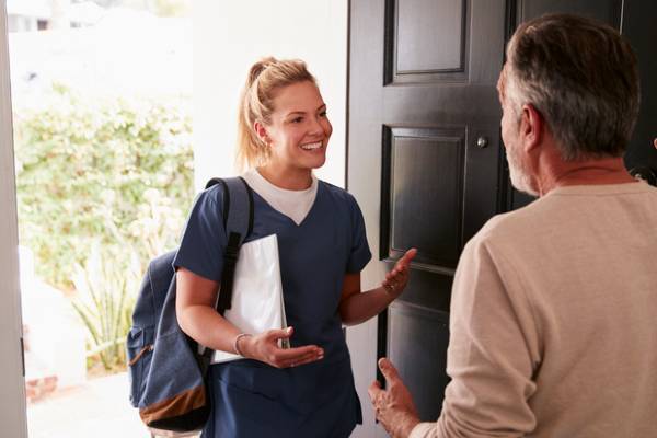 A community health worker going door to door talks to a community member