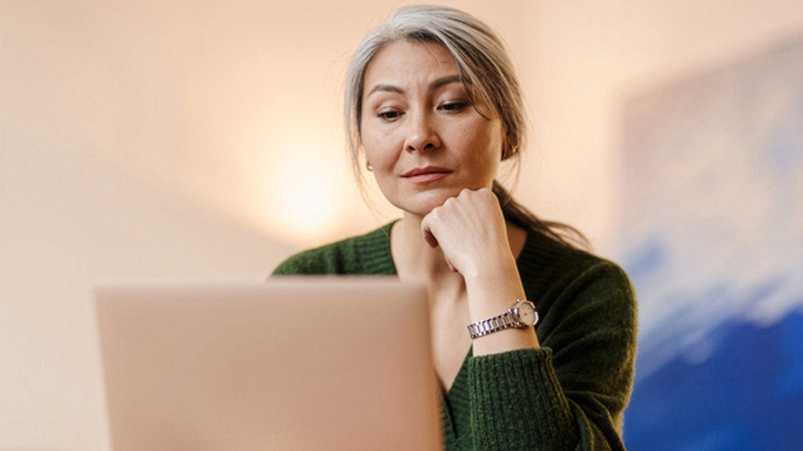 A woman learning about college accreditation on her laptop.