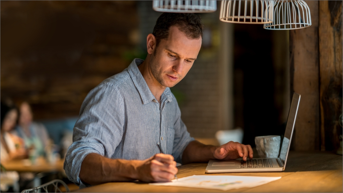 A man working on his laptop in a coffee shop.