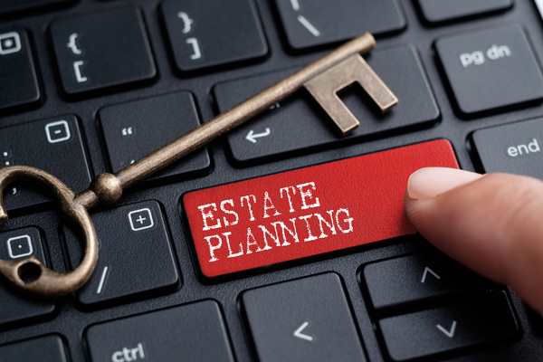 Finger pressing "Estate Planning" key on a keyboard next to an old-fashioned key.