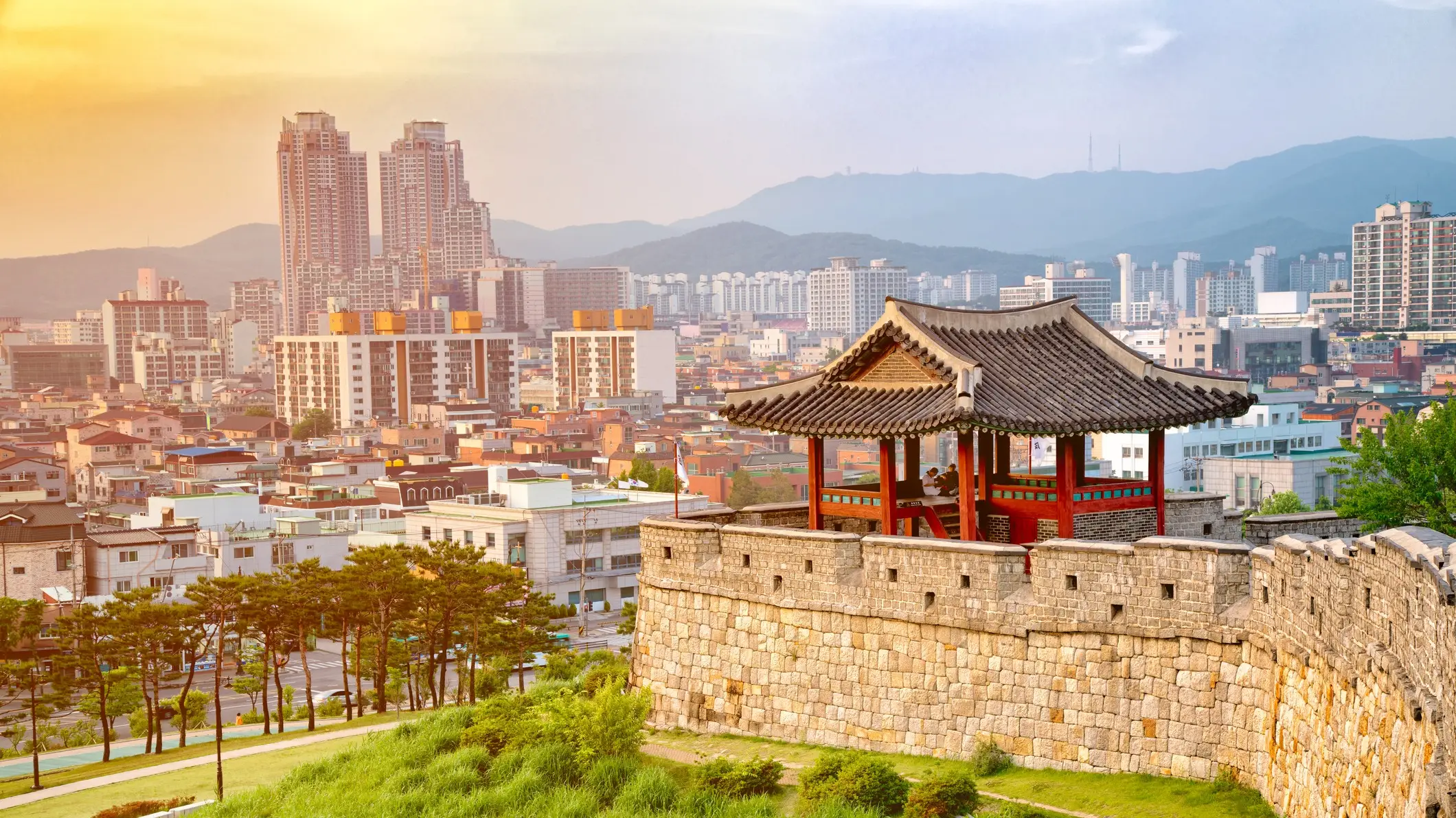 Festung in Suwon mit Stadt-Skyline im Hintergrund bei Sonnenuntergang