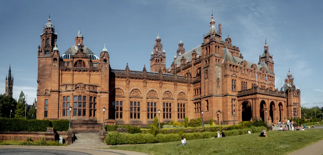 Menschen genießen das sonnige Wetter vor der Kelvingrove Art Gallery and Museum in Glasgow
