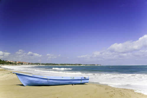 Der Strand von Cabarete mit einem blauen Boot