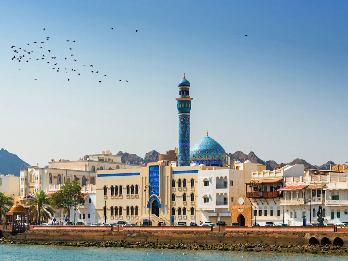  Blaue Kuppelmoschee und traditionelle Architektur am Hafen, umgeben von Bergen, Maskat, Oman.