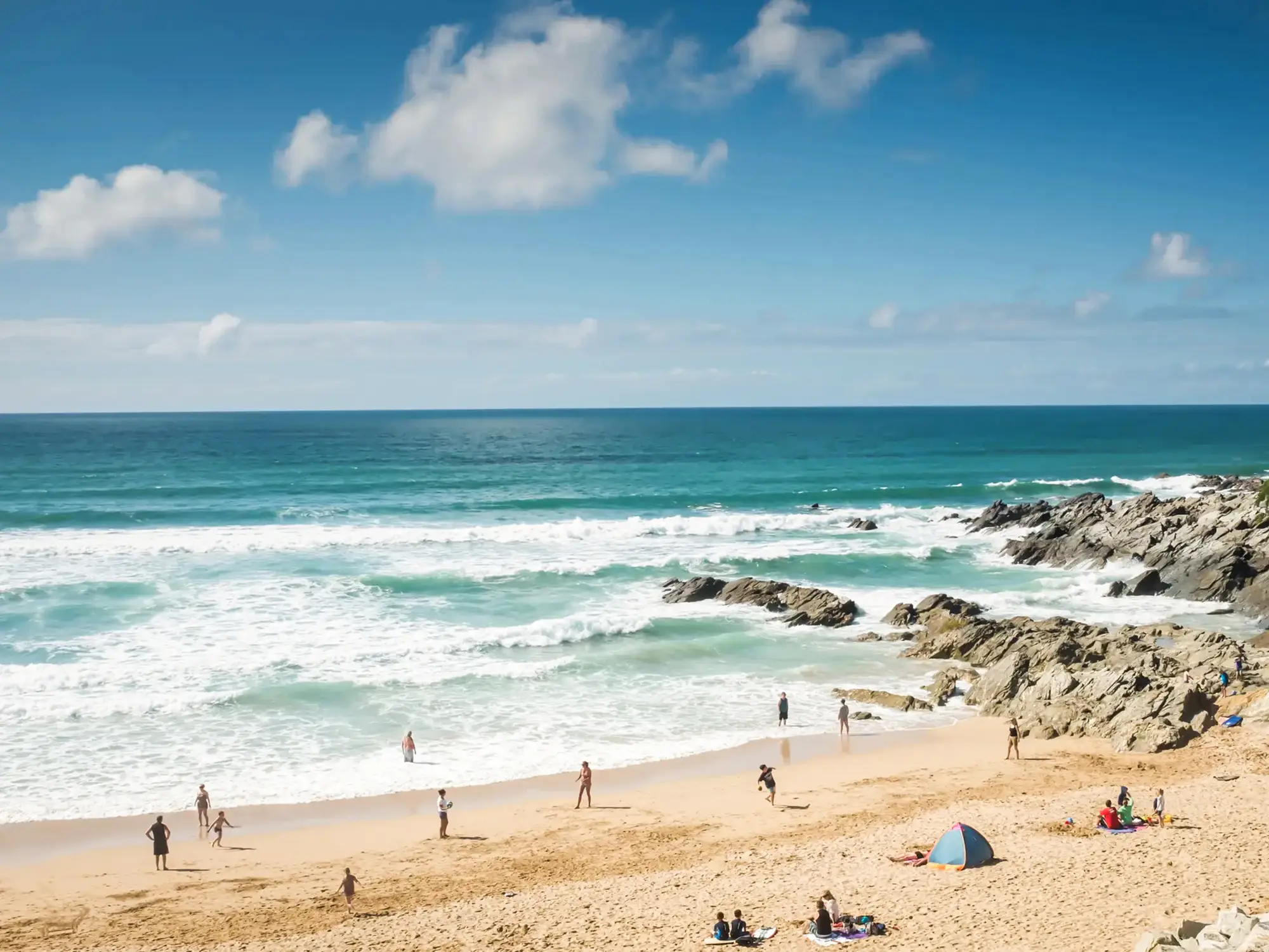 Beliebter Sandstrand mit hohen Wellen und Surfern an der Küste von Cornwall. Fistral Beach, Cornwall, England.