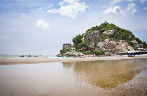 Der Strand von Hua Hin in Thailand mit einer großen goldenen stehenden Buddha-Statue im Hintergrund