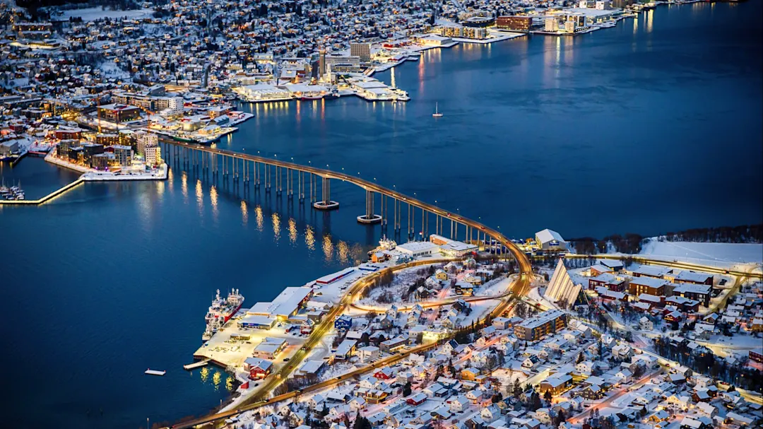 Luftbild von Tromsø mit Brücke und Hafen bei Nacht. Tromsø, Troms og Finnmark, Norwegen.