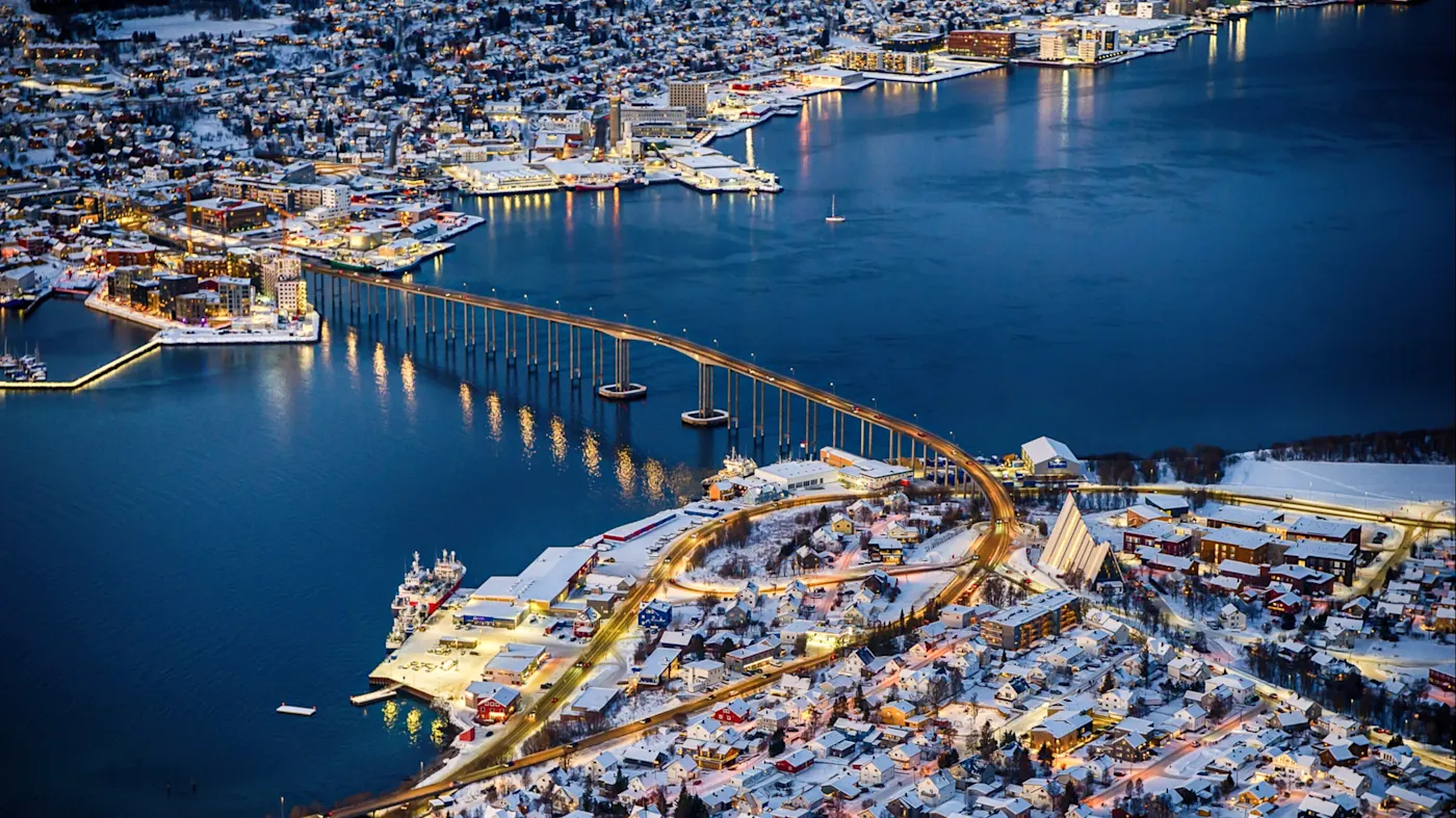 Luftbild von Tromsø mit Brücke und Hafen bei Nacht. Tromsø, Troms og Finnmark, Norwegen.