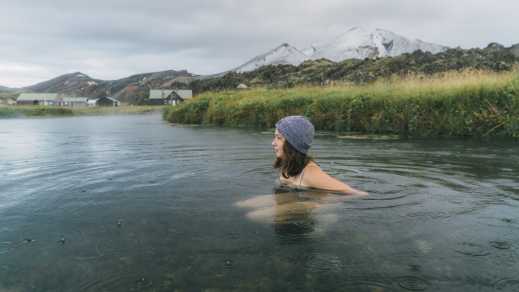 Une femme se repose dans une piscine naturelle en Islande.