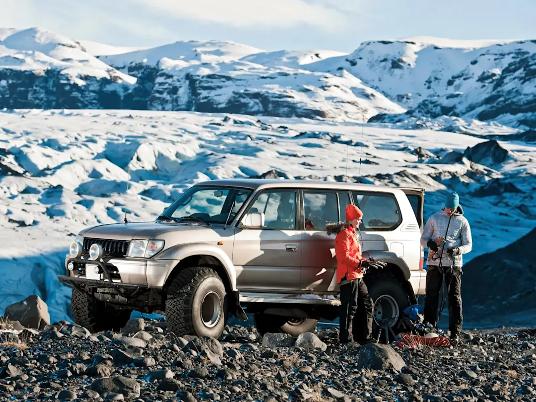 Geländewagen mit Winterausrüstung vor schneebedeckten Bergen. Island.