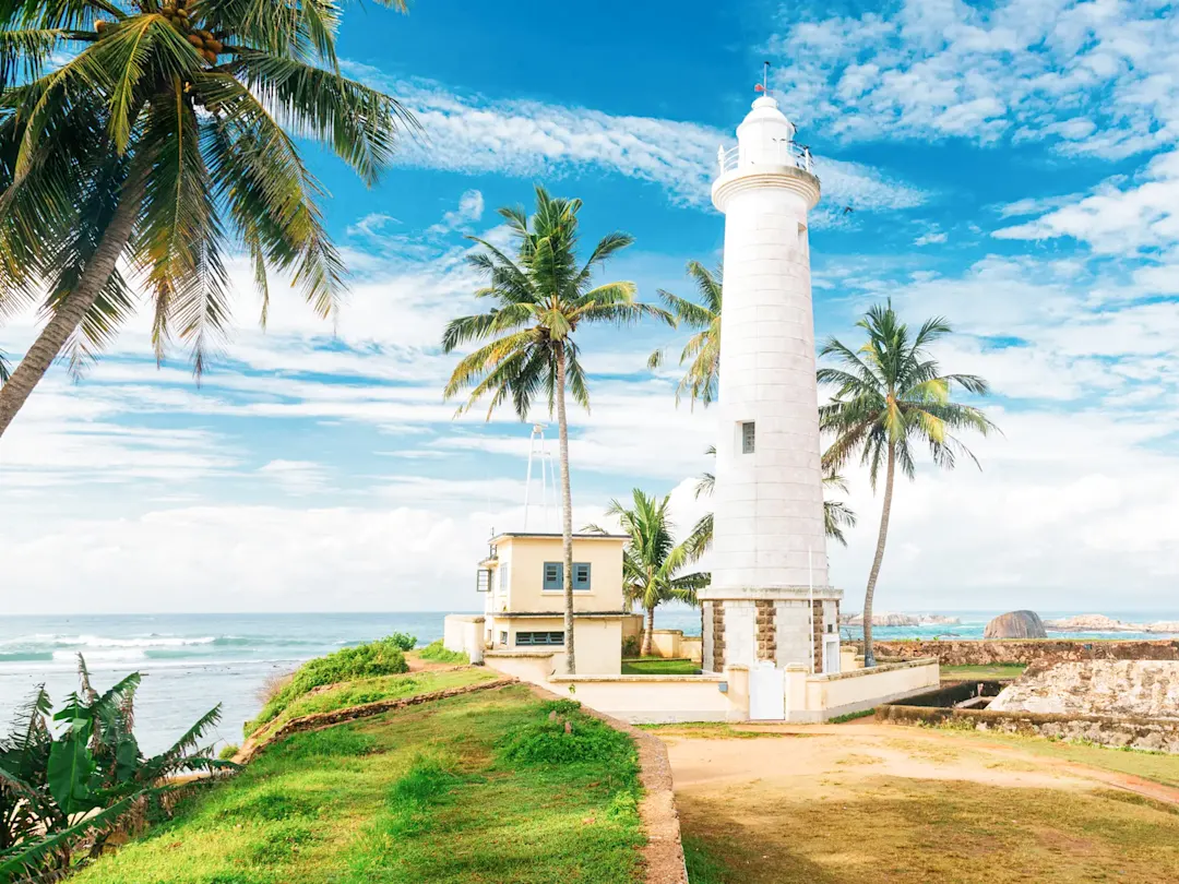 Sri Lanka, Familienurlaub Weißer Leuchtturm, Palmen, tropische Pflanzen, grünes Gras, Küstenlandschaft. Sri Lanka.