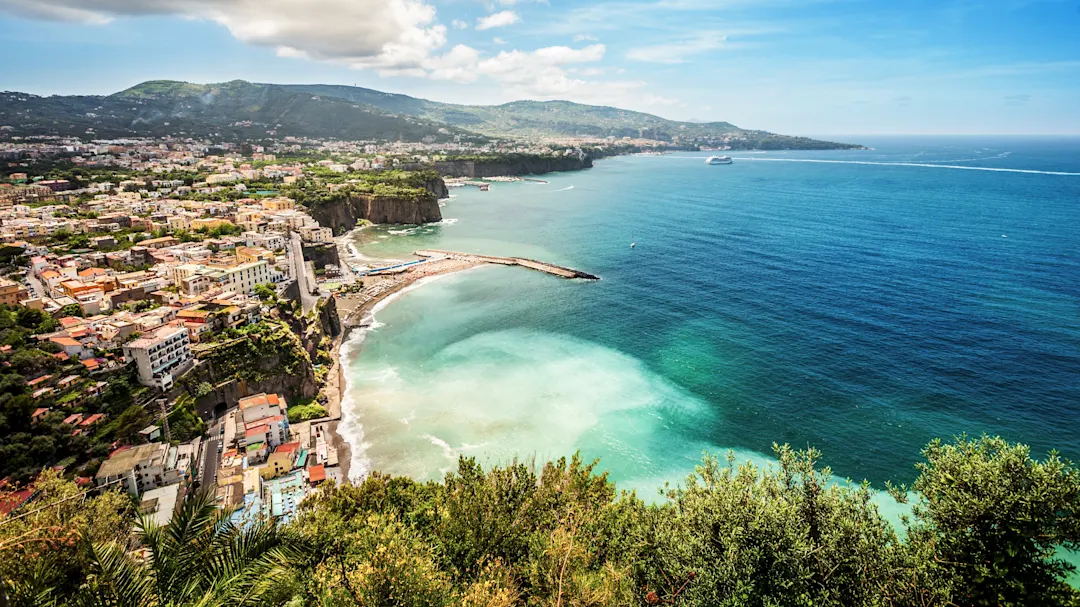 Küstenansicht von Sorrento mit dem Meer, den Hügeln und der Stadt im Hintergrund, Sorrento, Kampanien, Italien.
