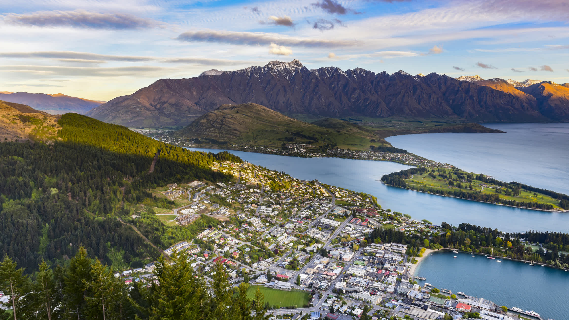 Vue aérienne sur les montagnes entourée d'eau au lever du soleil à Queenstown, en Nouvelle-Zélande