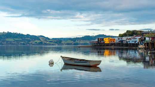 Un bateau de pêche solitaire à côté des maisons sur pilotis de Palafitos à Castro, île de Chiloe, Chili.