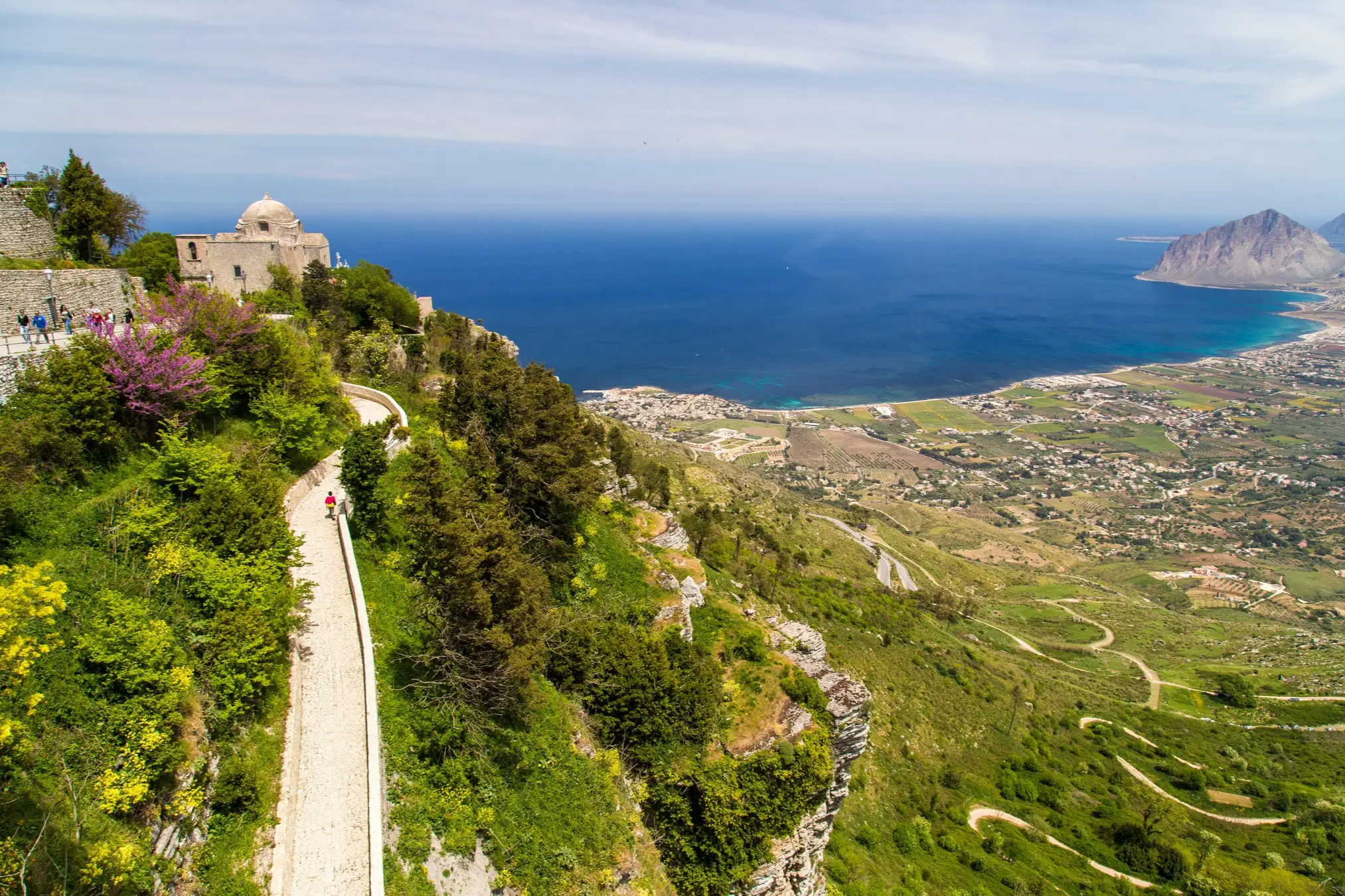 Vue sur une ancienne route de montagne qui mène au village d'Erice avec la mer en arrière-plan.