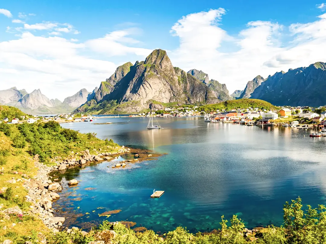 Malerisches Fischerdorf am Fjord mit dramatischen Bergen. Reine, Nordland, Norwegen.