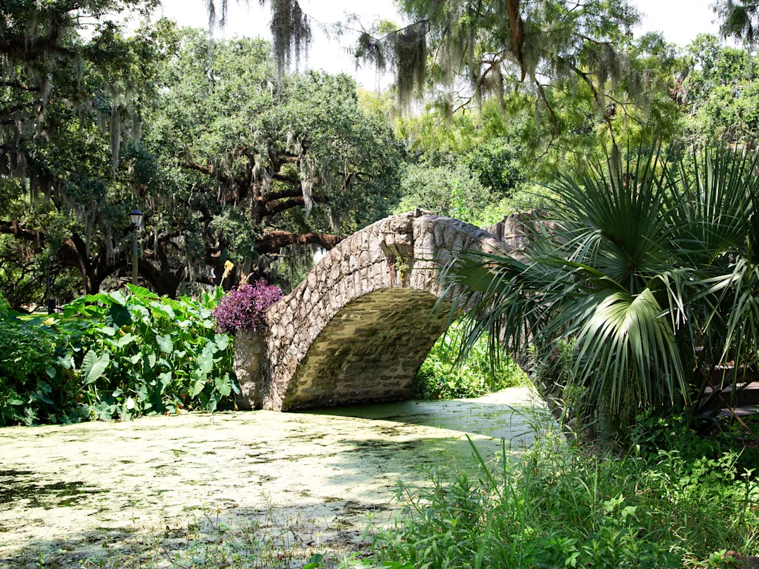 Steinbrücke über einen Teich in einem üppig bewachsenen Park. New Orleans, Louisiana, USA.