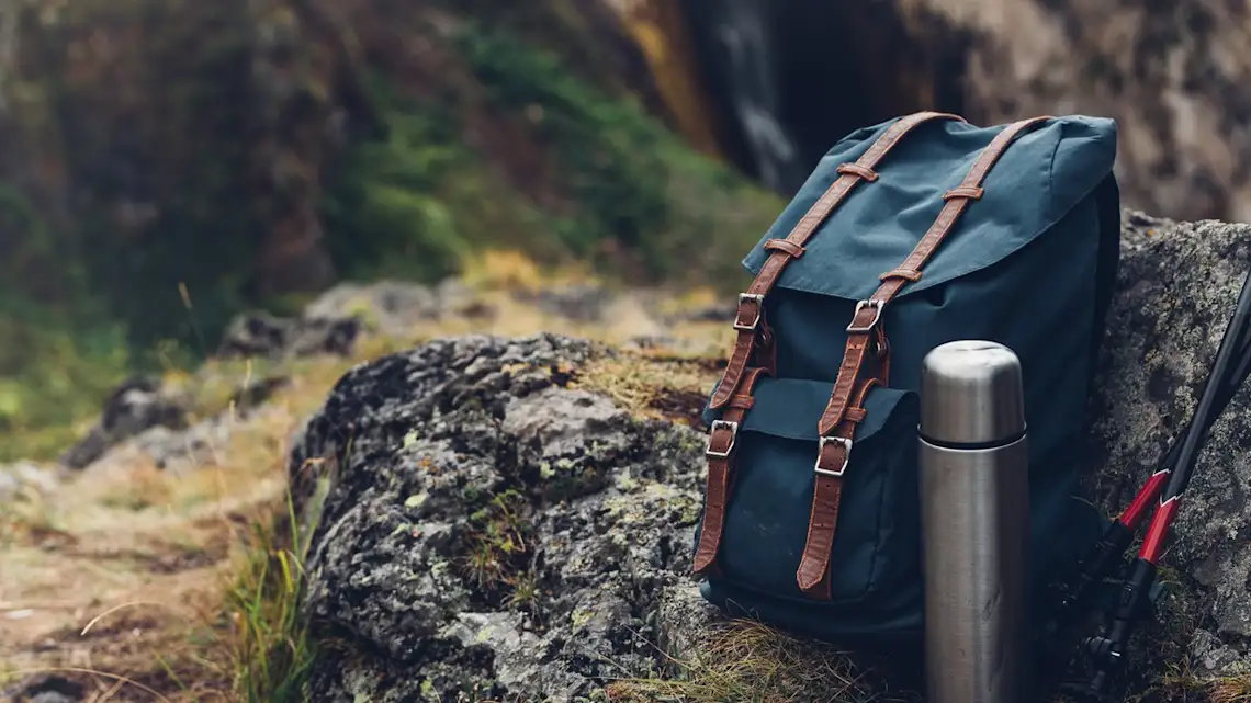 Laos, équipement de randonnée Sac à dos de randonnée et thermos sur une pierre dans la forêt