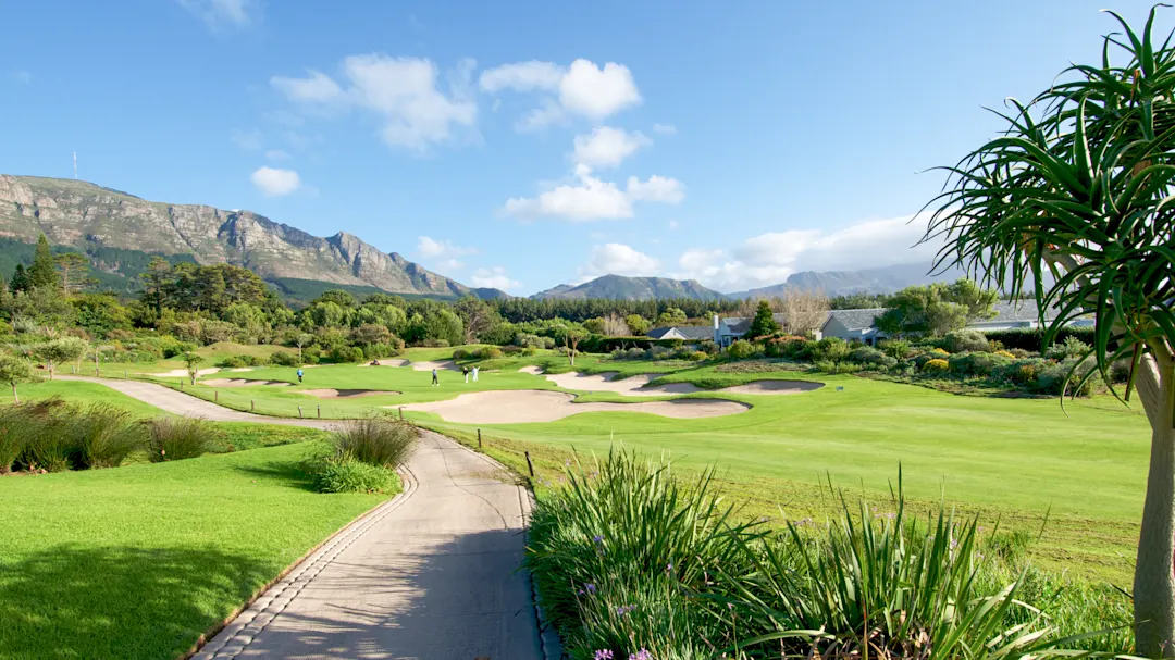 Gepflegter Golfplatz mit grünen Fairways und Sandbunkern vor einer Bergkulisse. Südafrika.