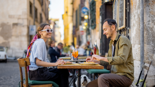 Ein Paar isst an einem kleinen Restaurant-Tisch im Freien.