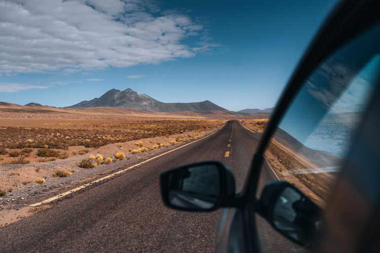 Vue depuis la voiture sur une route et des montagnes dans le désert d'Atacama lors d'un road trip au Chili
