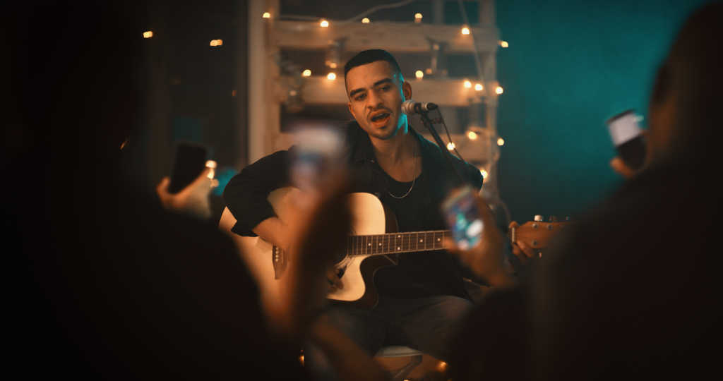 Young man singing and playing the guitar on stage in the club. 