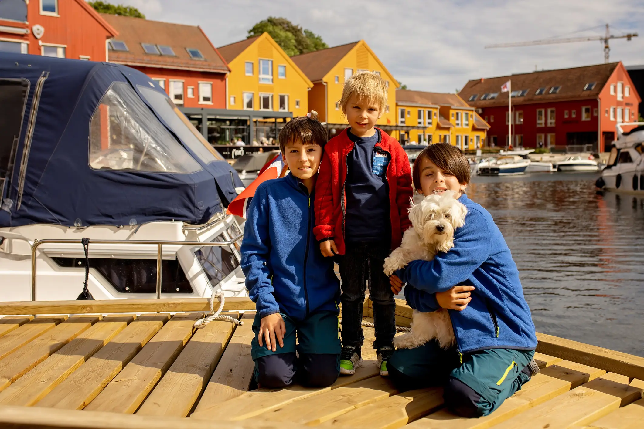 Norwegen, Kristiansand, Familienurlaub Kinder mit einem Hund auf dem Holzsteg in Kristiansand, Norwegen.