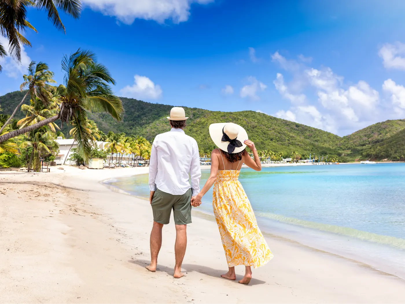 Reiseart, Flitterwochen Ein Paar hält Händchen an einem paradiesischen Strand.