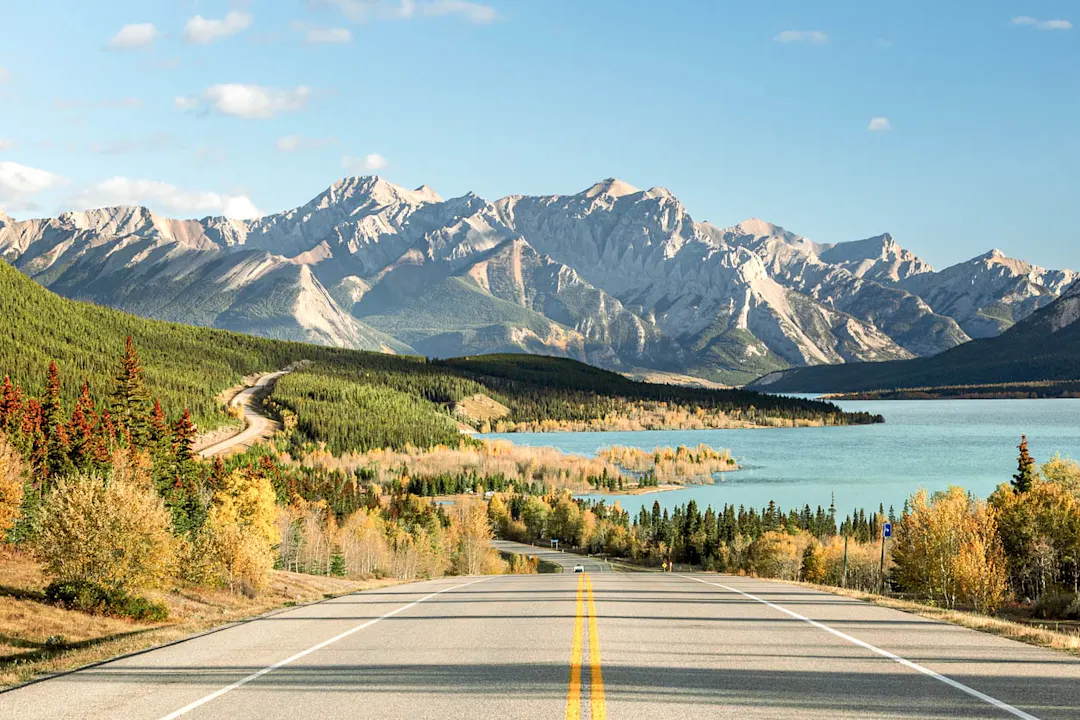 Bergstraße, die zum türkisfarbenen See und zum herbstlichen Wald in Alberta führt