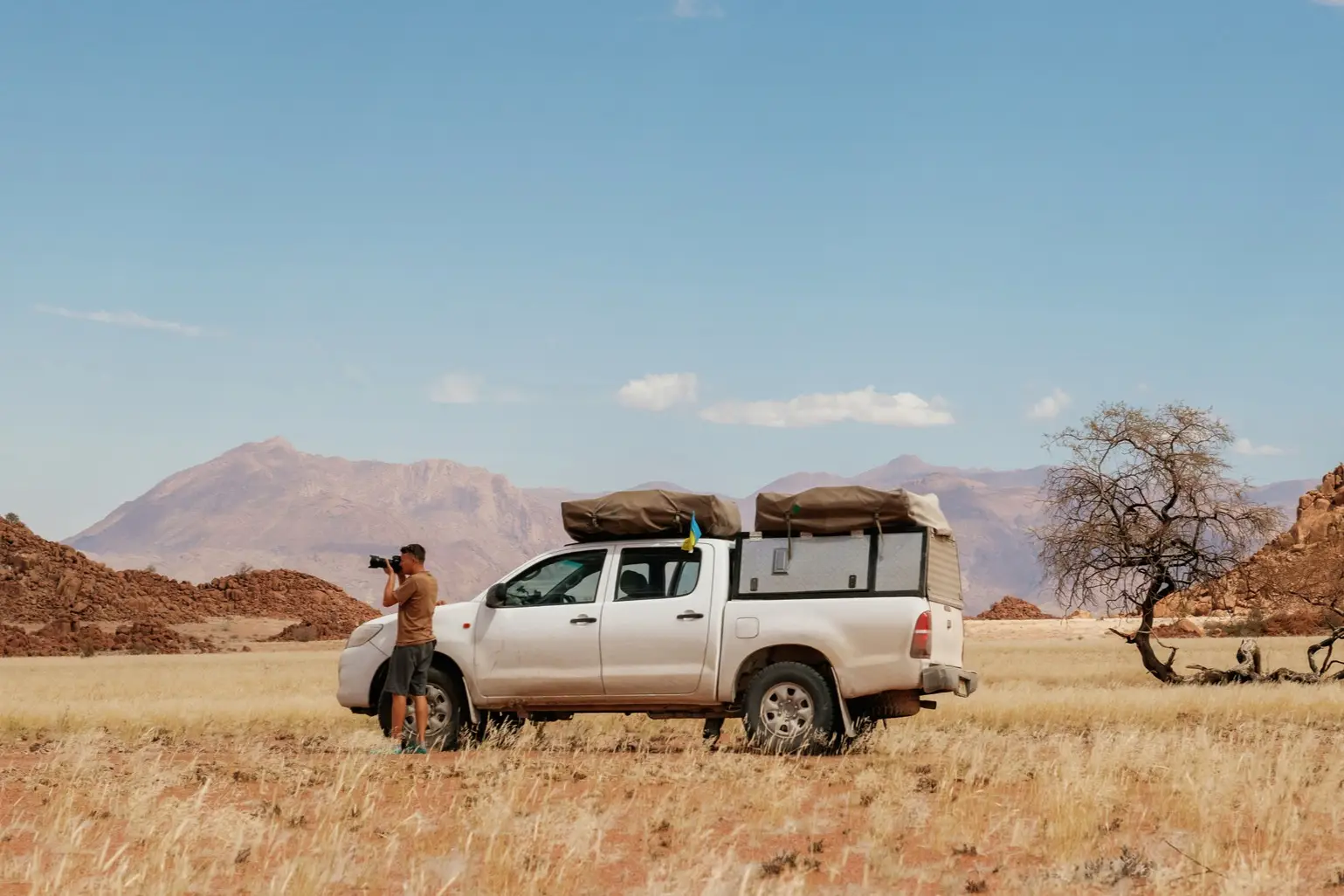 Fotograf in der Nähe eines Autos, das sich in den Wüsten Afrikas, Namibia, befindet.

