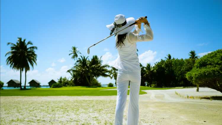 Une femme qui joue au golf sur un terrain en bord de mer à l'île Maurice.

