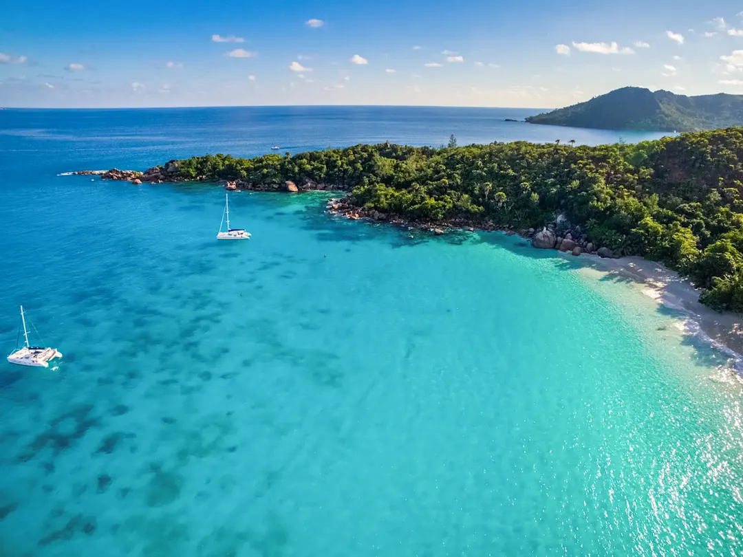  Luftaufnahme einer tropischen Bucht mit türkisblauem Wasser und Segelbooten. Seychellen.