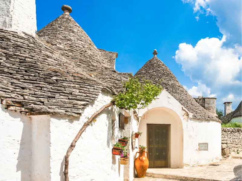Alberobello, Apulien, Italien Traditionelle Trulli-Häuser mit weißen Wänden und kegelförmigen Dächern unter blauem Himmel, Alberobello, Italien.